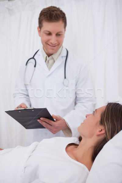 Stock photo: Doctor with clipboard talking with bedridden patient