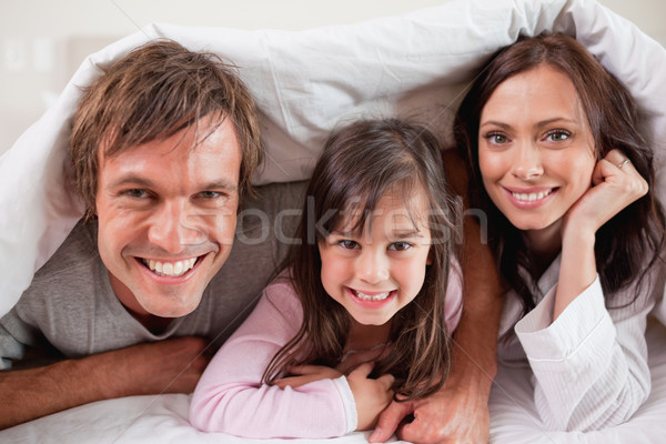Happy parents lying under a duvet with their daughter in their bedroom Stock photo © wavebreak_media