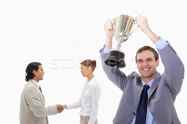 Stock photo: Businessman raising cup with hand shaking colleagues behind him against a white background