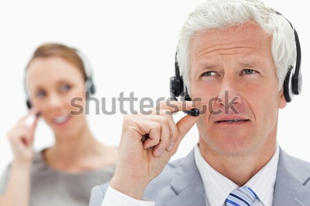 Close-up of a white hair man with a woman talking in background while wearing a headset against whit Stock photo © wavebreak_media