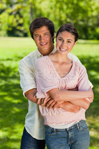 Man and woman smiling as he has his arms around her abdomen in a park Stock photo © wavebreak_media