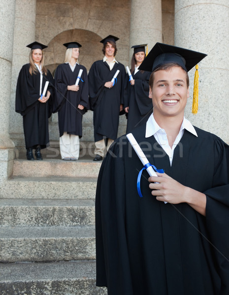 Close-up of a blue eyes graduate smiling with her friends in background in front of the university Stock photo © wavebreak_media