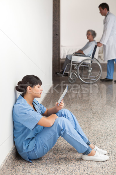 Nurse reading sitting on floor in hospital corridor Stock photo © wavebreak_media