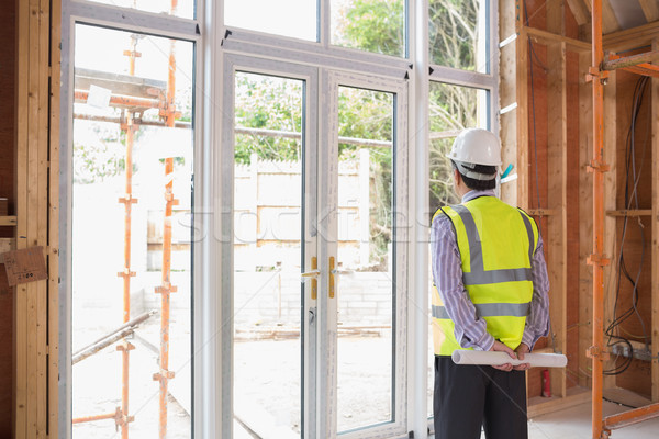 Architect holding a plan while looking outside and standing in the house Stock photo © wavebreak_media