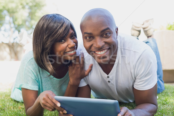 Stock photo: Happy couple lying in garden using tablet pc together