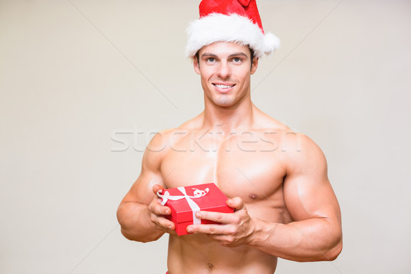 Shirtless macho man in santa hat holding gift Stock photo © wavebreak_media