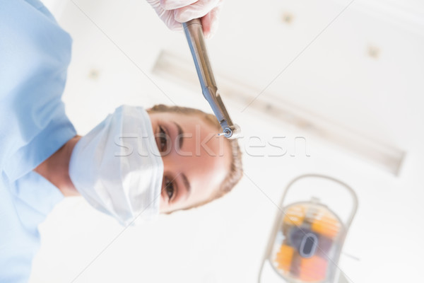 Dentist in surgical mask holding dental drill over patient Stock photo © wavebreak_media