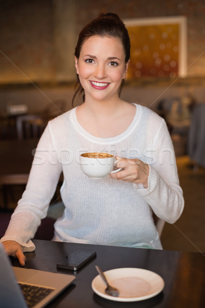Pretty brunette having coffee using laptop Stock photo © wavebreak_media