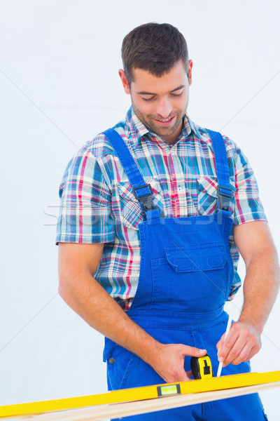 Stock photo: Carpenter marking on plank with tape measure