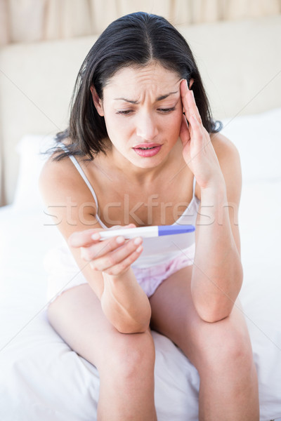 Pretty brunette holding a pregnancy test on bed Stock photo © wavebreak_media