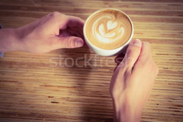 Hands holding cappuccino with coffee art Stock photo © wavebreak_media