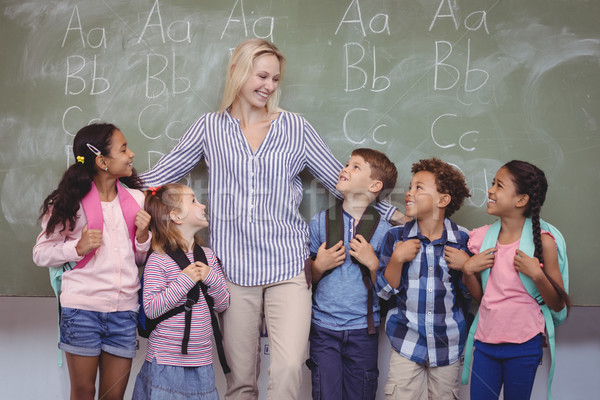 Happy teacher standing with schoolkids in classroom Stock photo © wavebreak_media