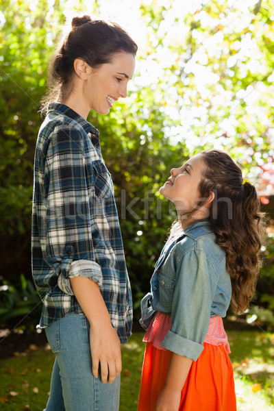 Stock photo: Side view of smiling mother and daughter standing in backyard