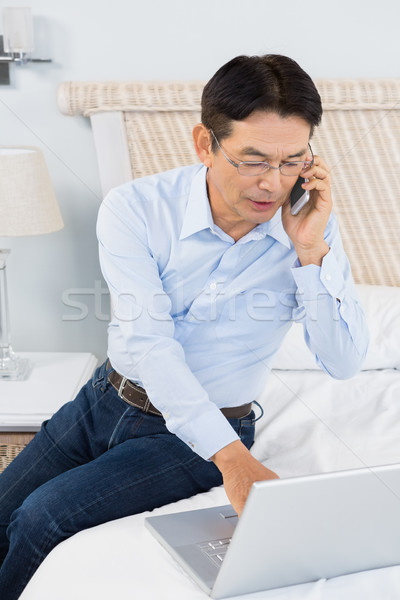 Hombre usando la computadora portátil dormitorio teléfono feliz Foto stock © wavebreak_media