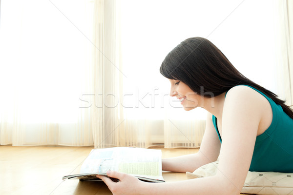 Interested woman reading a magazine lying down on the floor Stock photo © wavebreak_media
