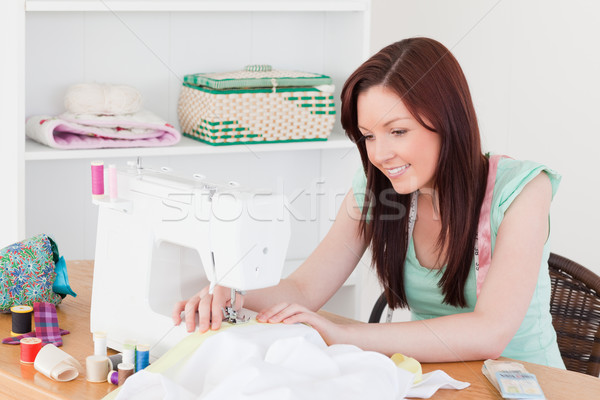 Pretty red-haired female using a sewing machine in her living room Stock photo © wavebreak_media