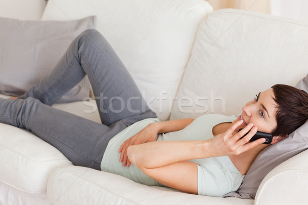 Calm brunette calling while lying on a sofa in her living room Stock photo © wavebreak_media