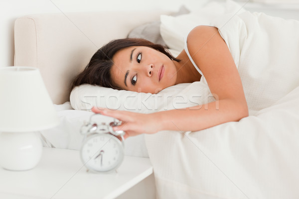 close up of a  cute woman waking under sheet turning off alarm clock in bedroom Stock photo © wavebreak_media