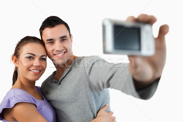 Young couple taking photograph of themselves against a white background Stock photo © wavebreak_media