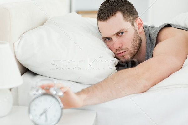 Man switching off his alarm clock in his bedroom Stock photo © wavebreak_media