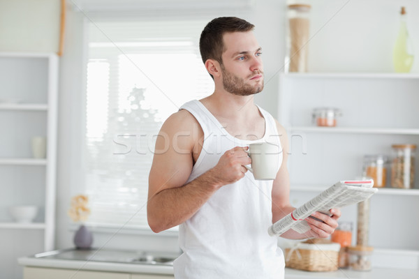 Dreaming man drinking tea while reading the news in his kitchen Stock photo © wavebreak_media