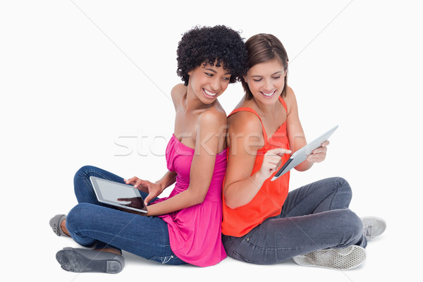 Smiling teenage proudly showing her tablet PC to her friend who is sitting cross-legged Stock photo © wavebreak_media
