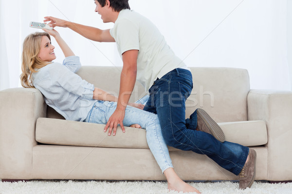 A man on a couch tries to get the television remote control off his girlfriend Stock photo © wavebreak_media