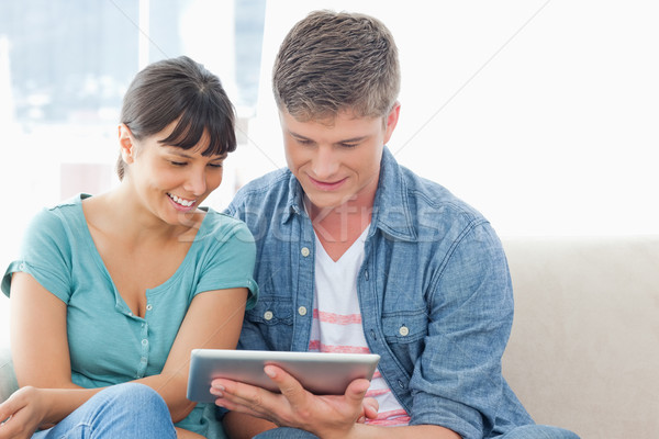 A smiling couple sitting together as they use a tablet pc  Stock photo © wavebreak_media