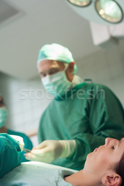 Patient sleeping on a surgical table while a surgeon is taking scissors in a surgical room Stock photo © wavebreak_media