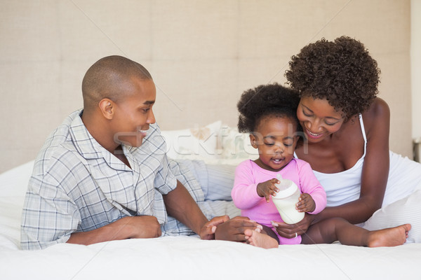 Stock photo: Happy parents and baby girl sitting on bed together