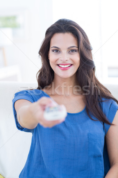 Smiling beautiful brunette relaxing on the couch and changing tv Stock photo © wavebreak_media