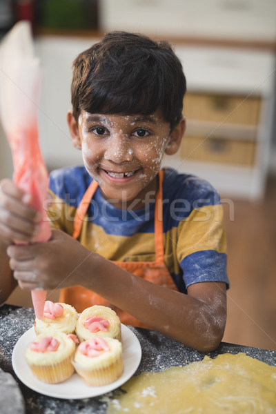 Stock photo: Portrait of happy boy making cup cakes in kitchen