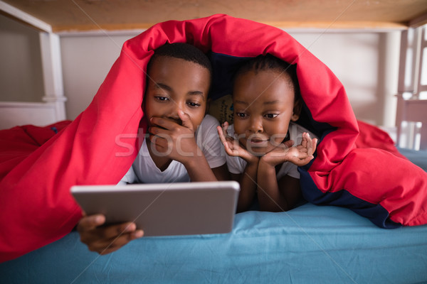 Surprised siblings holding digital tablet while lying on bed Stock photo © wavebreak_media