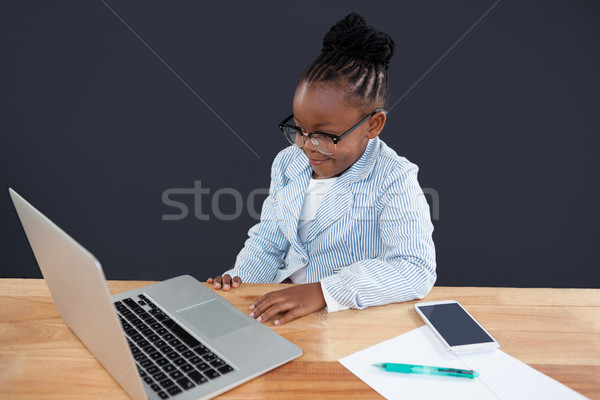 Smiling businesswoman wearing eyeglasses looking laptop Stock photo © wavebreak_media