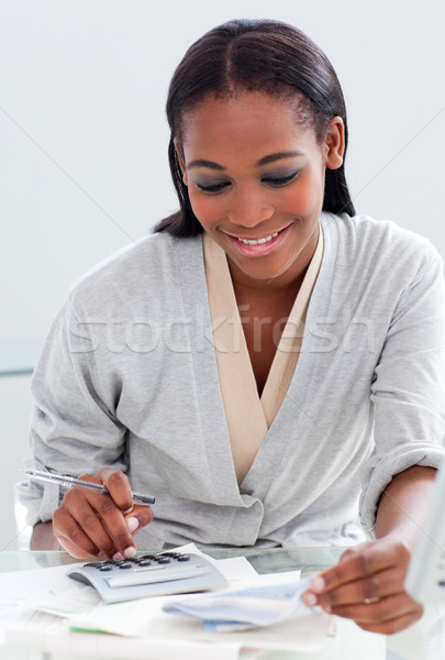 Smiling businesswoman using a calculator at her desk Stock photo © wavebreak_media