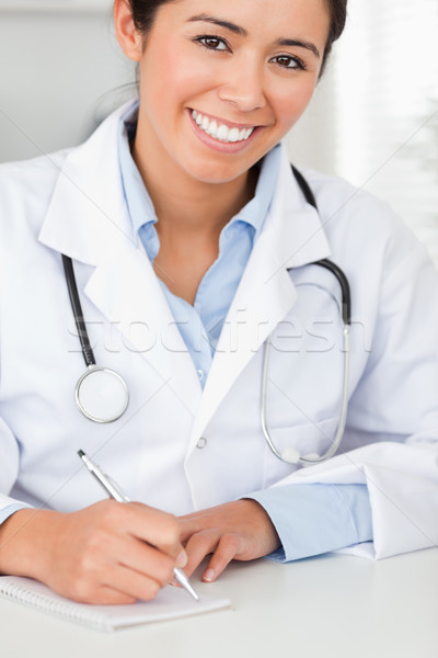 Good looking female doctor writing on a scratchpad in her office Stock photo © wavebreak_media