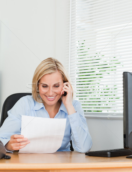 Businesswoman phoning and reeding a paper in her office Stock photo © wavebreak_media