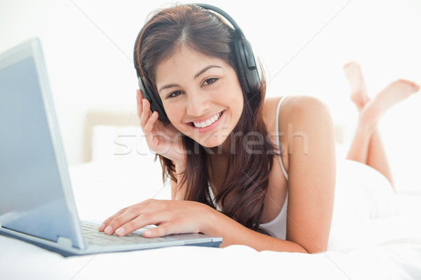 Kobieta relaks bed za pomocą laptopa słuchawki skrzyżowanymi nogami Zdjęcia stock © wavebreak_media