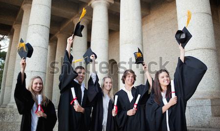 Graduates holding up their hats in front of the university Stock photo © wavebreak_media