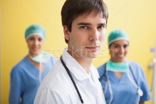 Doctor in labcoat with two smiling nurses in scrubs in background Stock photo © wavebreak_media