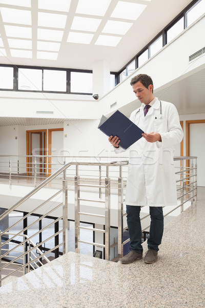 Doctor looking in his folder in hospital hallway Stock photo © wavebreak_media