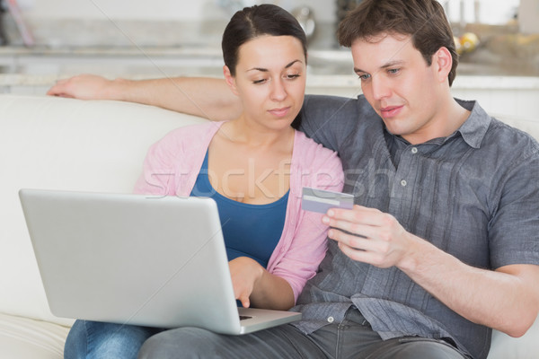 Two Young People Sitting On The Couch While Using The Laptop And
