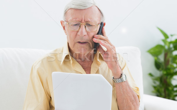 Idoso homem leitura documentos telefone casa Foto stock © wavebreak_media