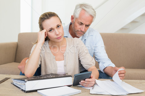 Stock photo: Serious couple calculating their bills at the couch