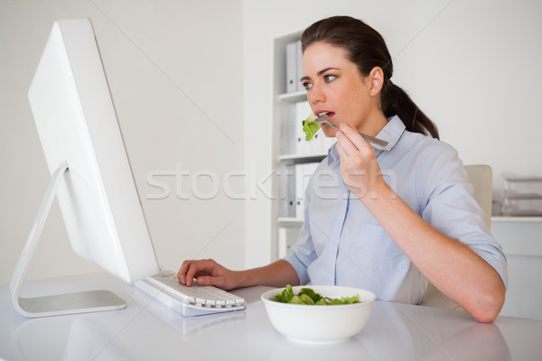 Casual morena mujer de negocios comer ensalada escritorio Foto stock © wavebreak_media