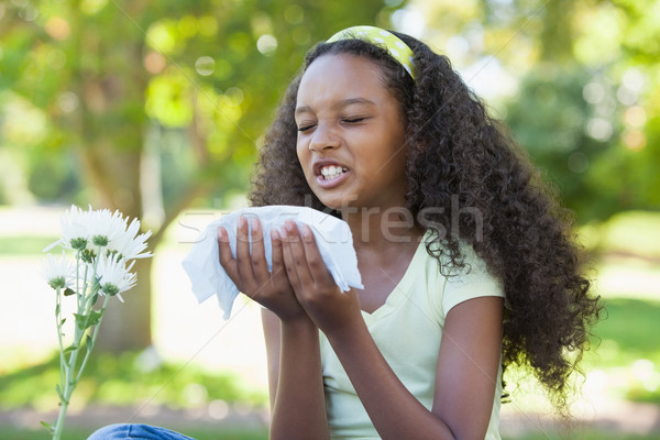 Young girl sitting by flower and sneezing in the park Stock photo © wavebreak_media