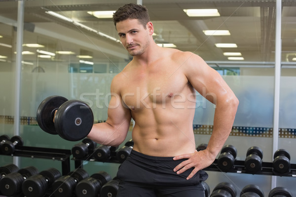 Stock photo: Shirtless bodybuilder lifting heavy black dumbbell looking at ca