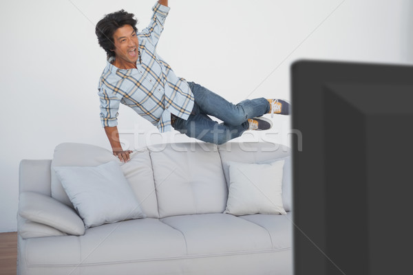 Happy soccer fan cheering while watching tv Stock photo © wavebreak_media