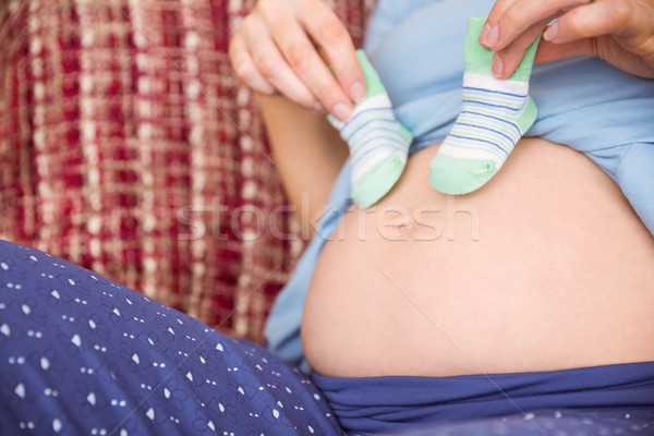 Pregnant woman holding baby shoes over bump Stock photo © wavebreak_media