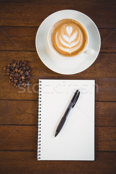 Cup of cappuccino with coffee art and notepad Stock photo © wavebreak_media